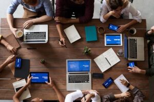 Overhead view of a diverse team in a business meeting using laptops and tablets.